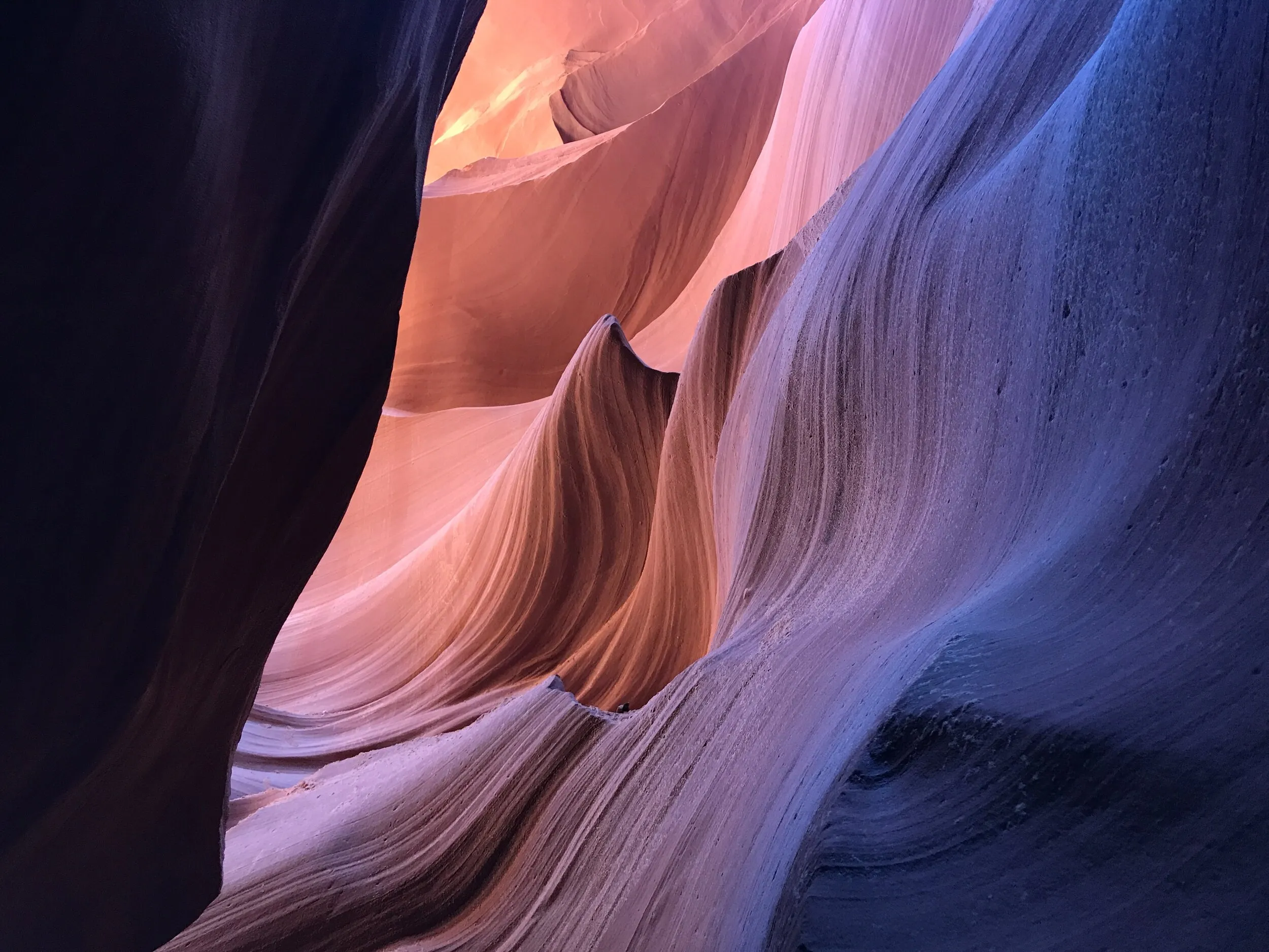 Curving slot-canyon walls illuminated in pink, orange, and blue.
